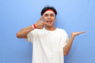 Beyaz tişörtlü Endonezyalı adam ve Endonezya bayrağı mutlu yüzüyle avucunun içini gösteriyor, Endonezya bağımsızlık günü konsepti