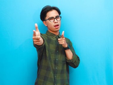 Mavi arka planda izole edilmiş kameraya bakan heyecanlı Asyalı adamın portresi