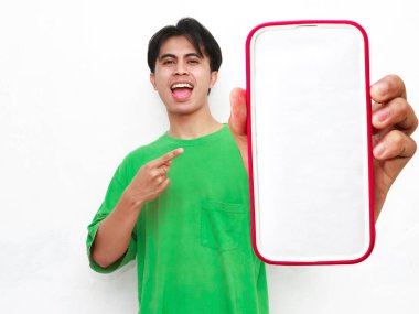 Yeşil tişört giyen, elinde akıllı bir telefon tutan ve beyaz arka planda izole edilmiş büyük boş bir ekran gösteren Asyalı genç bir adamın portresi..