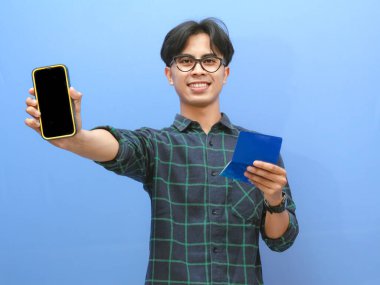 Cep telefonlu genç Asyalı adam ve izole edilmiş beyaz arka planda boş ekran gösteriyor