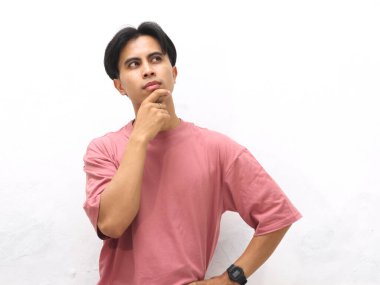 Pembe tişörtlü genç Asyalı adam, beyaz bir arkaplanda gözleri olduğunu düşünüyor..