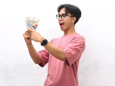 Pembe tişörtlü mutlu bir Asyalı adamın portresi. Elinde para tutuyordu. Heyecanlı bir ifade vardı..