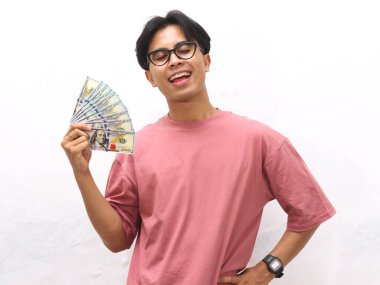 Pembe tişörtlü mutlu bir Asyalı adamın portresi. Elinde para tutuyordu. Heyecanlı bir ifade vardı..