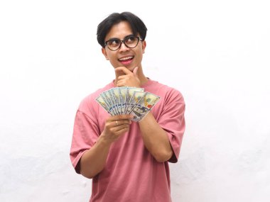 Pembe gömlekli genç bir Asyalı 'nın portresi. Elinde para tutuyordu. Beyaz arka planda düşünceli bir ifadeyle yukarı bakıyordu.