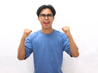 Neşeli genç Asyalı bir adamın portresi yüzünde mutlu bir gülümsemeyle yumruğunu kaldırdı.