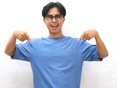 Mavi tişörtlü genç Asyalı adam boş fotokopi alanını gösteriyor. Promosyon veya reklam içeriği için ideal..