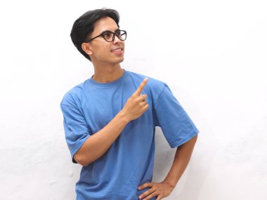 Mavi tişörtlü genç Asyalı adam boş fotokopi alanını gösteriyor. Promosyon veya reklam içeriği için ideal..