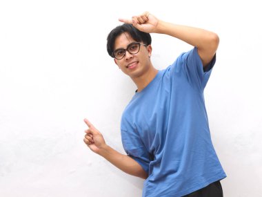 Mavi tişörtlü genç Asyalı adam boş fotokopi alanını gösteriyor. Promosyon veya reklam içeriği için ideal..