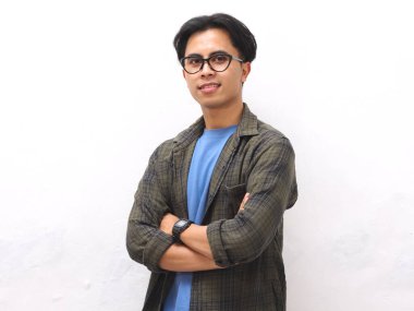 Gülümseyen, mavi tişörtlü, kolları çapraz duran, beyaz arka planda yalnız, kendinden emin, Asyalı genç bir adam.