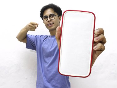 Mavi tişörtlü genç Asyalı adam boş bir telefon ekranı tutarken gülümsüyor. Beyaz arka planda boş ekran telefon gösteren yakışıklı Asyalı bir adam..