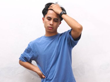 Stresli Asyalı genç adam beyaz arka planda mavi tişört giyiyor..