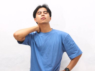 Stresli Asyalı genç adam beyaz arka planda mavi tişört giyiyor..