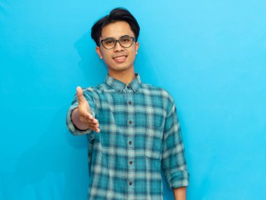 Mavi Stüdyo Arkaplanında Gülümseyen ve El sıkışan Asyalı Mutlu Asyalı Adam. Tanıştığımıza memnun oldum.