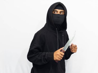 Siyah ceketli ve maskeli bir suçlu, bıçak tutuyor, sinsi bir jest yapıyor, soyuyor ve beyaz bir arka planda suç işliyor..