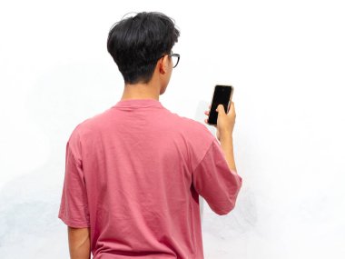 Pembe tişört giyen Asyalı genç adam beyaz arka planda izole cep telefonu kullanıyor..
