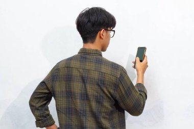 Elinde tuttuğu cep telefonuna bakan bir adamın arka görüntüsü