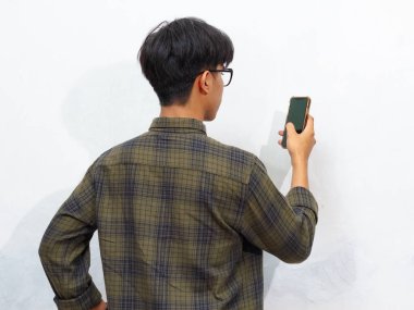 Elinde tuttuğu cep telefonuna bakan bir adamın arka görüntüsü