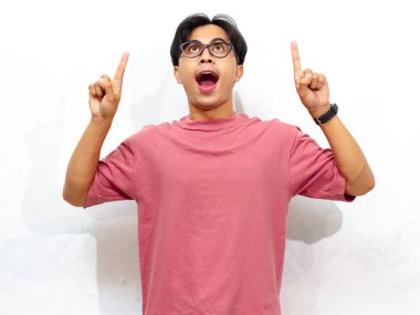 Pembe tişörtlü heyecanlı genç Asyalı adam beyaz arka planda izole edilmiş, reklamlar için mükemmel..