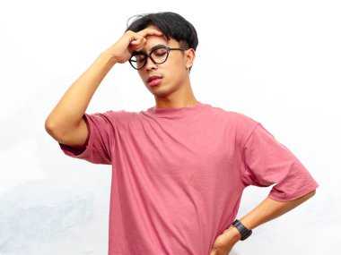 Pembe tişörtlü genç bir Asyalı 'nın portresi, beyaz bir arka plana karşı stresli ve hayal kırıklığına uğramış bir ifade gösteriyor..