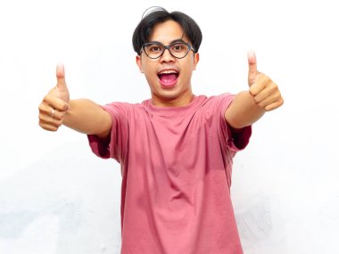 Pembe tişörtlü heyecanlı genç Asyalı adam beyaz arka planda izole bir şekilde kameraya doğru işaret veriyor..