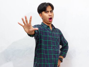 Yakışıklı Asyalı bir gencin portresi. Dur ya da Reddet ifadesini gösteriyor. Kollarını kavuşturuyor..