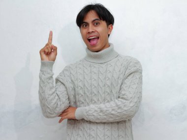 Beyaz bir arka planda izole bir şekilde kameraya bakarken yukarı bakan mutlu, heyecanlı Asyalı bir adamın portresi. Reklamcılık ve promosyonlar için mükemmel. 