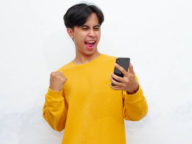 Mutlu Asyalı genç adam beyaz arka planda izole akıllı telefon tutuyor.