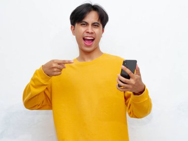 Mutlu Asyalı genç adam beyaz arka planda izole akıllı telefon tutuyor.