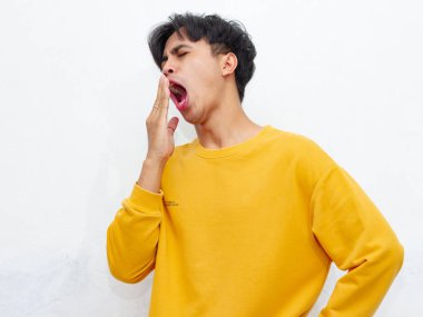 Portrait of asian man yawning and covering wide open mouth with hand isolated on white background clipart