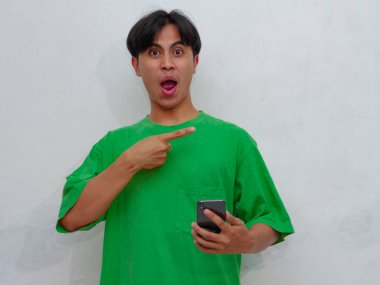 Akıllı telefon tutan komik Asyalı adam beyaz bir arka planda izole edilmiş, şaşırmış bir 