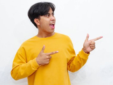 Şaşırmış Asyalı bir adamın portresi reklam için boş bir alanı işaret ediyor, beyaz arka planda komik ve şok edici bir ifadeyle. Promosyon ve pazarlama için mükemmel..