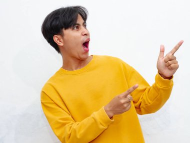 Şaşırmış Asyalı bir adamın portresi reklam için boş bir alanı işaret ediyor, beyaz arka planda komik ve şok edici bir ifadeyle. Promosyon ve pazarlama için mükemmel..