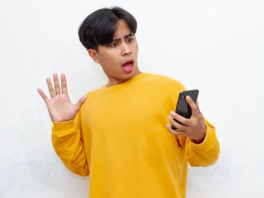 Şaşırmış bir ifadeyle Asyalı bir adamın portresi, beyaz bir arka planda, cep telefonu tutarken poz veriyor. Reklam, teknoloji ve yaşam tarzı temaları için mükemmel.