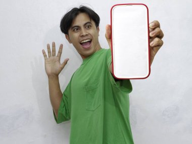 Asyalı bir adamın portresi. Şaşırmış bir ifadeyle boş bir cep telefonu ekranı gösteriyor. Reklam, uygulama ve promosyon içeriği için mükemmel..