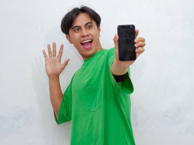 Asyalı bir adamın portresi. Şaşırmış bir ifadeyle boş bir cep telefonu ekranı gösteriyor. Reklam, uygulama ve promosyon içeriği için mükemmel..