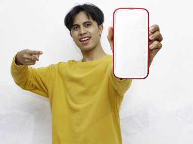 Beyaz arka planda boş ekranlı akıllı telefon gösteren heyecanlı Asyalı genç adam
