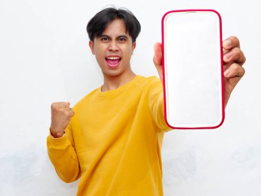 Beyaz arka planda boş ekranlı akıllı telefon gösteren heyecanlı Asyalı genç adam