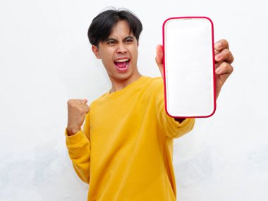 Beyaz arka planda boş ekranlı akıllı telefon gösteren heyecanlı Asyalı genç adam