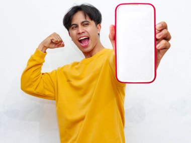 Beyaz arka planda boş ekranlı akıllı telefon gösteren heyecanlı Asyalı genç adam