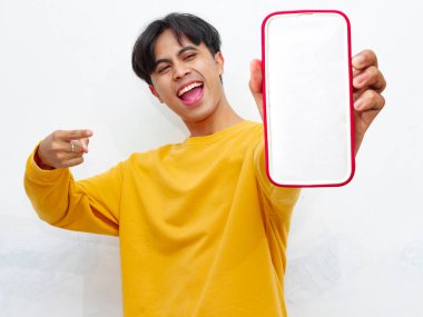 Beyaz arka planda boş ekranlı akıllı telefon gösteren heyecanlı Asyalı genç adam
