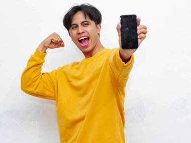 Beyaz arka planda boş ekranlı akıllı telefon gösteren heyecanlı Asyalı genç adam