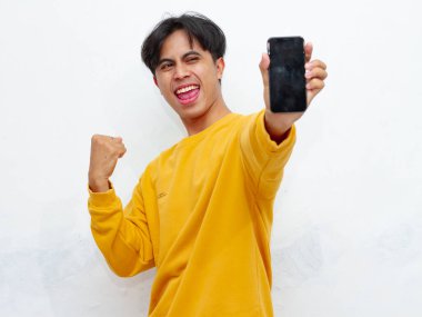 Beyaz arka planda boş ekranlı akıllı telefon gösteren heyecanlı Asyalı genç adam