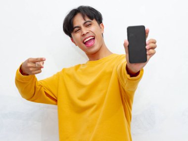Beyaz arka planda boş ekranlı akıllı telefon gösteren heyecanlı Asyalı genç adam