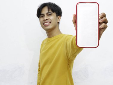 Beyaz arka planda boş ekranlı akıllı telefon gösteren heyecanlı Asyalı genç adam