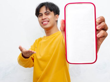 Beyaz arka planda boş ekranlı akıllı telefon gösteren heyecanlı Asyalı genç adam