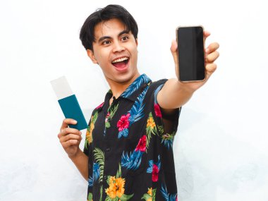 Genç Asyalı 'nın portresi günlük giysiler giyer. Pasaport tutar ve boş cep telefonu ekranı gösterir. Beyaz arka planda izole edilmiş mutlu ekspresyonlar..