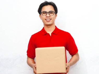 Elinde paketle gülümseyen Asyalı teslimatçı, alıcıya teslim etmeye hazır. Beyaz arka planda izole edilmiş, dağıtım, lojistik ve kurye kavramları için ideal..