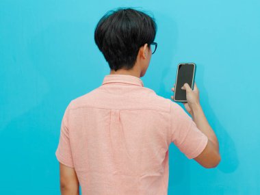 Elinde tuttuğu cep telefonuna bakan bir adamın arka görüntüsü