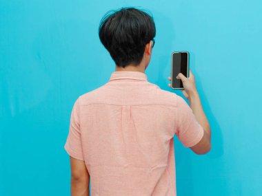 Elinde tuttuğu cep telefonuna bakan bir adamın arka görüntüsü