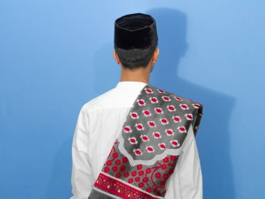 Asyalı Müslüman Adam 'ın mavi arka planda duran Müslüman kıyafetleri giydiği arka plan